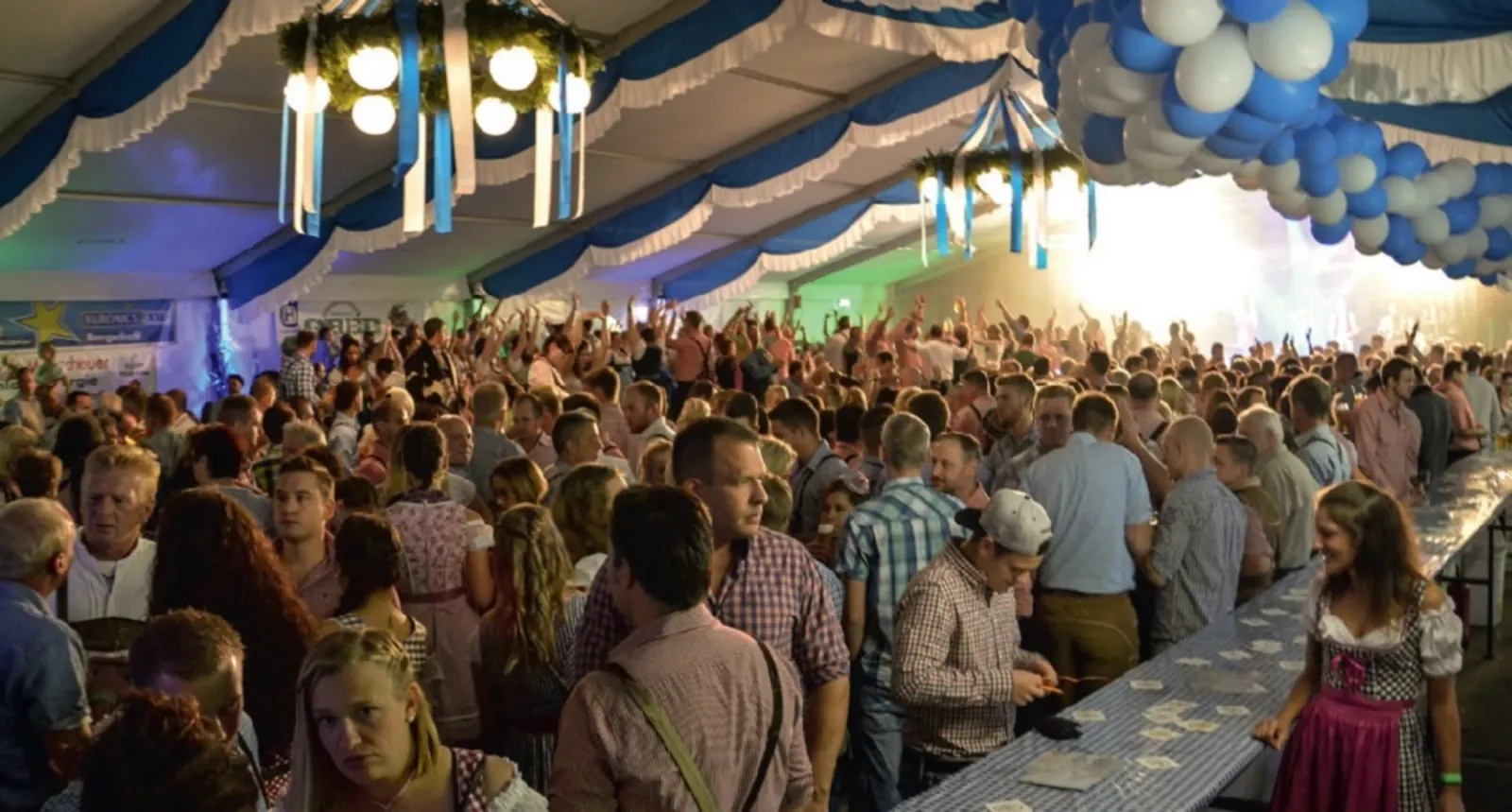 Volles Festzelt in Vierbuchermühle: blau-weiß geschmückte Zeltdecke, lange Biertische und feiernde Gäste, viele in Tracht